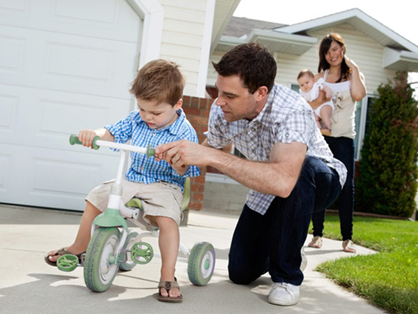 Father helping son ride a tricycle